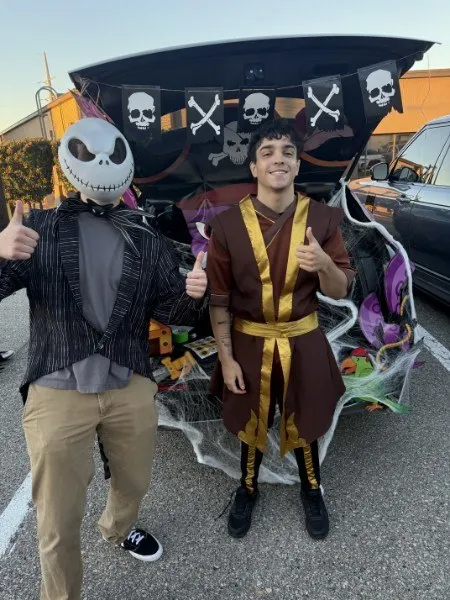 Two instructors in costume beside a decorated car boot at a past Trunk or Treat